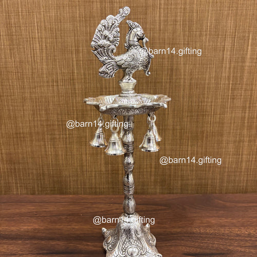 Silver finish five wick peacock diya stand with hanging bells, traditional lamp for Diwali, pooja, and festive rituals, symbol of prosperity and devotion.