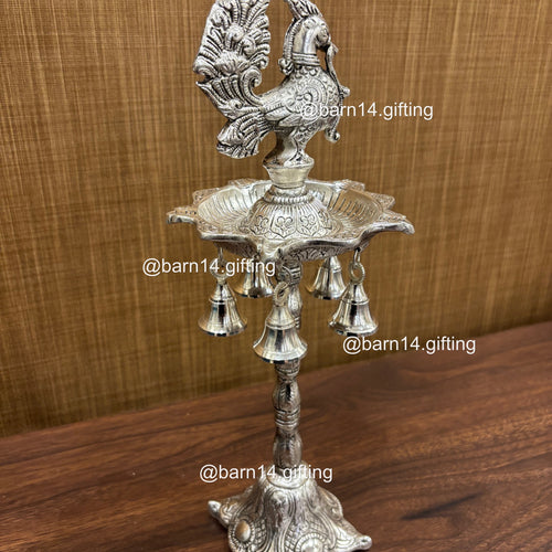 Silver finish five wick peacock diya stand with hanging bells, traditional lamp for Diwali, pooja, and festive rituals, symbol of prosperity and devotion.